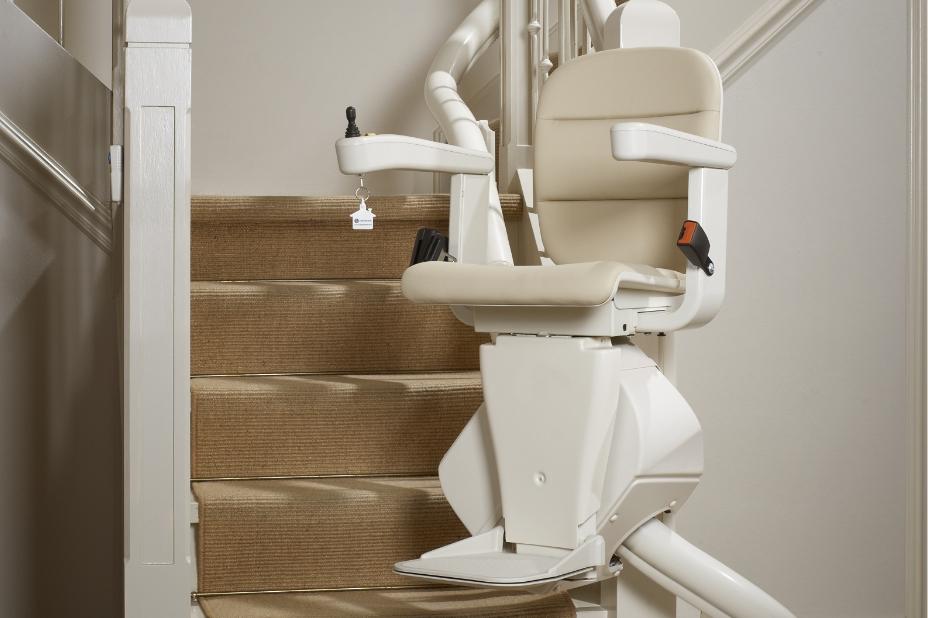 Cream curved stairlift in use, moving up the stairs