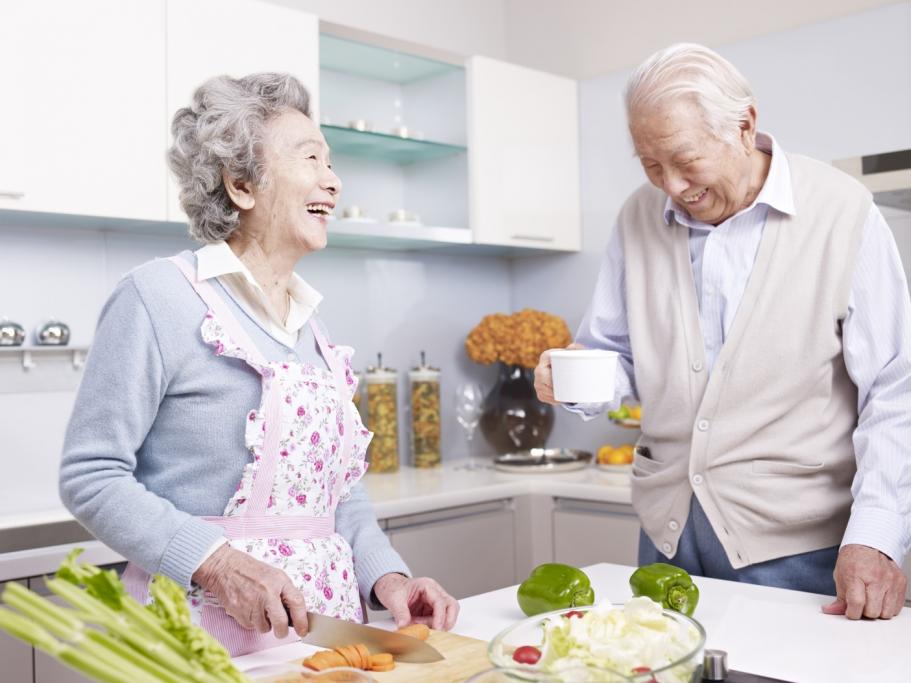 Elderly couple laughing and cooking in the kitchen